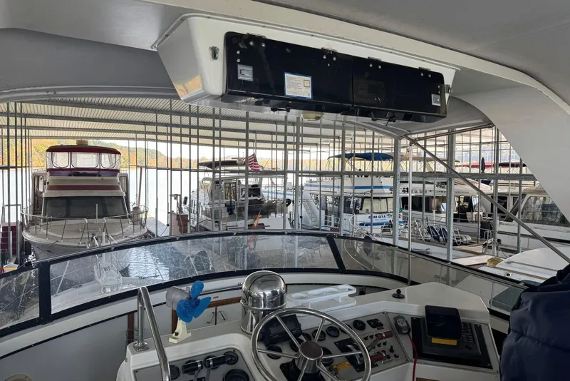 Slide: The Image of 1987 Carver 42 Aft Cabin Motor Yacht helm in marina, surrounded by docked boats. - 16