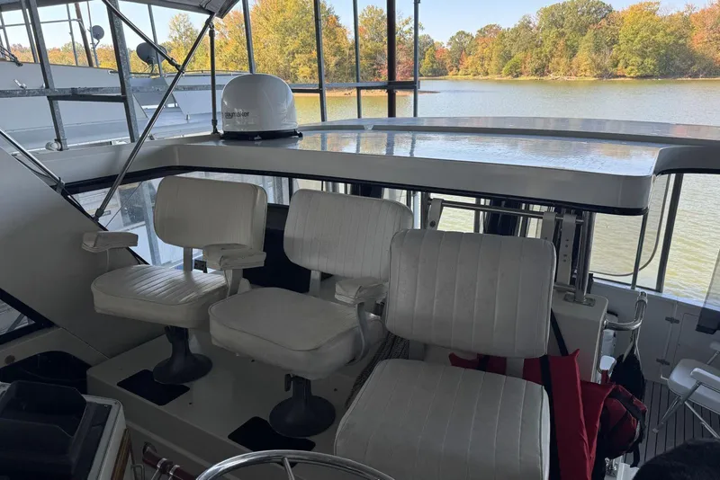 Slide: The Image of 1987 Carver 42 Aft Cabin Motor Yacht helm with white captain chairs, overlooking serene lake. - 22