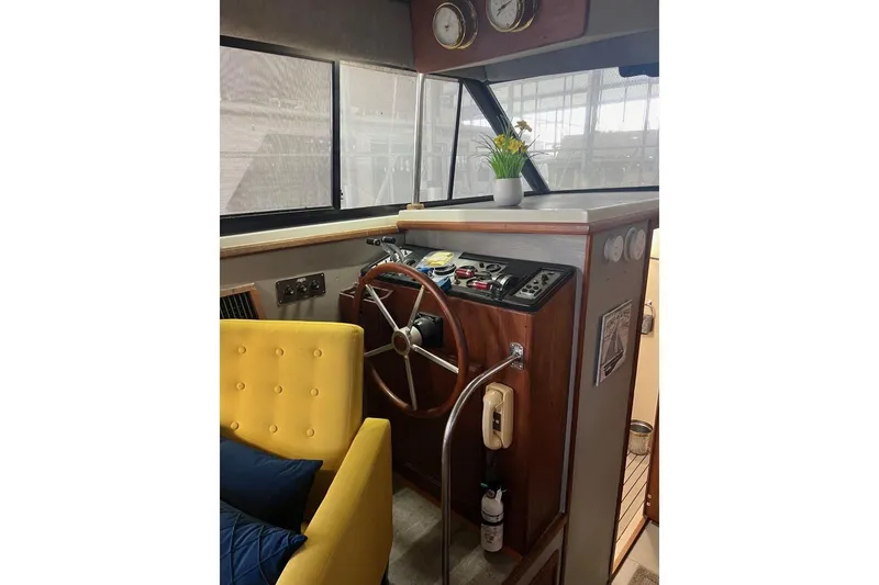 Slide: The Image of 1987 Carver 42 Aft Cabin Motor Yacht helm with wooden steering wheel and cozy seating. - 28