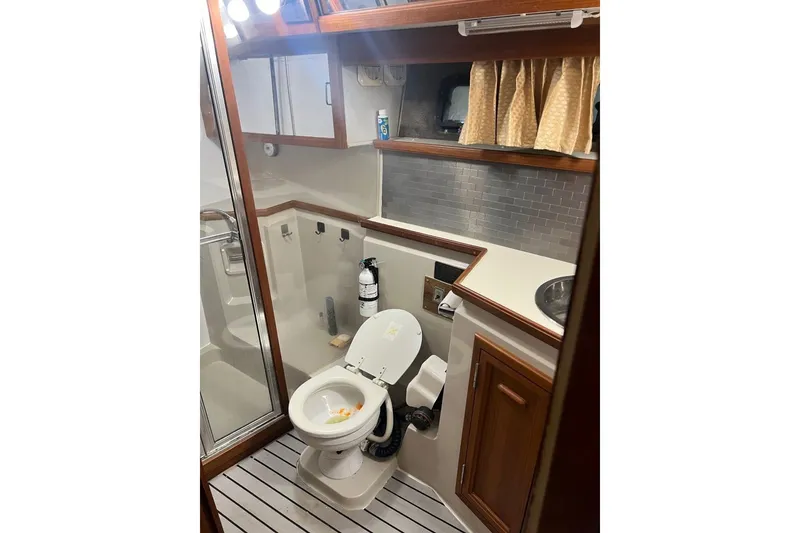 Slide: The Image of 1987 Carver 42 Aft Cabin Motor Yacht bathroom with toilet, sink, and wooden cabinetry. - 34