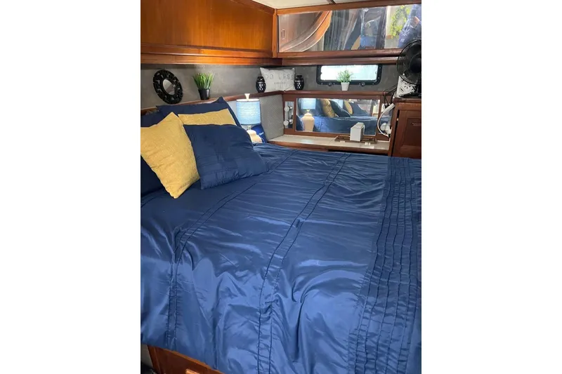 Slide: The Image of Luxurious bedroom in 1987 Carver 42 Aft Cabin Motor Yacht with blue bedding and wooden accents. - 44