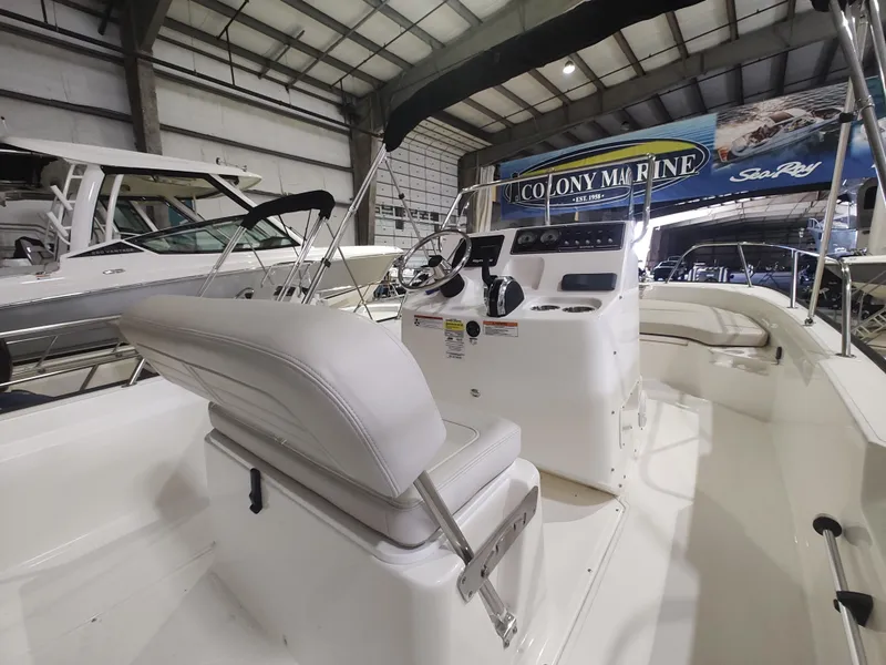 Slide: The Image of 2022 Boston Whaler 190 Montauk boat interior in showroom, featuring helm and seating. - 13