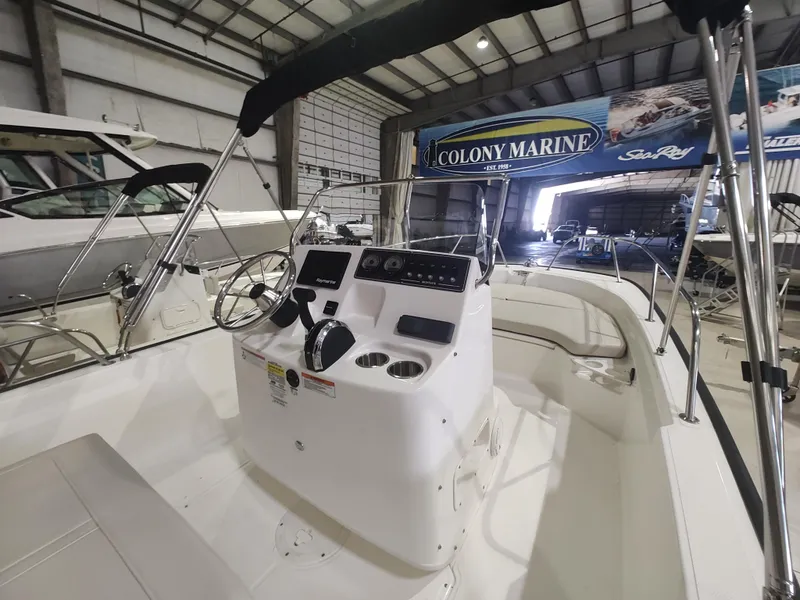 Slide: The Image of 2022 Boston Whaler 190 Montauk boat interior in showroom, featuring steering console and seating. - 18