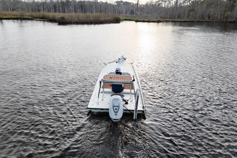 Slide: The Image of 2019 Skimmer Skiff 16'6" CC boat on a calm lake, viewed from behind. - 20