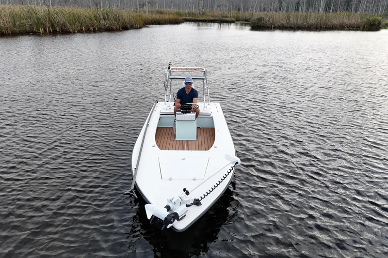 Slide: The Image of 2019 Skimmer Skiff 16'6" CC boat on calm water with a person at the helm. - 22