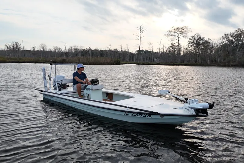 Slide: The Image of 2019 Skimmer Skiff 16'6" CC boat on calm water with a person seated. - 23