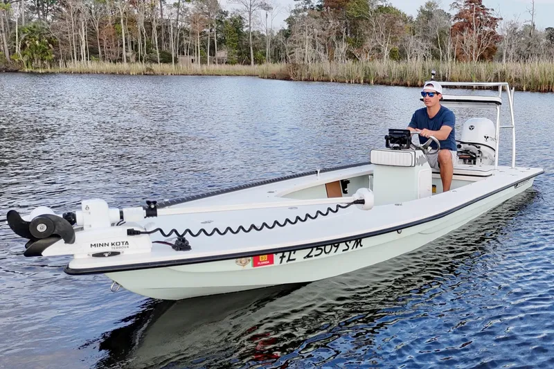 Slide: The Image of 2019 Skimmer Skiff 16'6" CC boat on water with driver, surrounded by trees. - 28