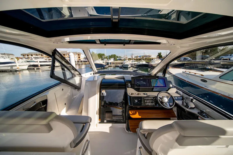 Slide: The Image of 2024 Sea Ray Sundancer 370 helm with modern controls and marina view. - 12