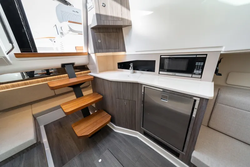 Slide: The Image of 2024 Sea Ray Sundancer 370 interior with modern kitchenette and wooden steps. - 33