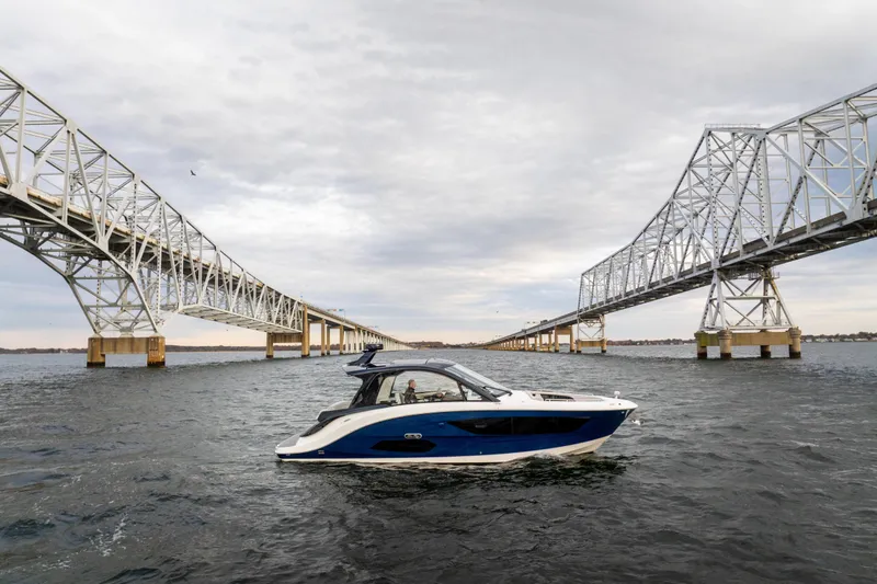 Slide: The Image of 2024 Sea Ray Sundancer 370 cruising under a large bridge on a cloudy day. - 5