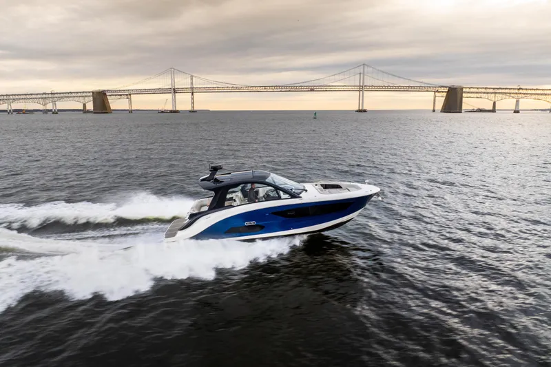 Slide: The Image of 2024 Sea Ray Sundancer 370 cruising on water near a large bridge at sunset. - 6