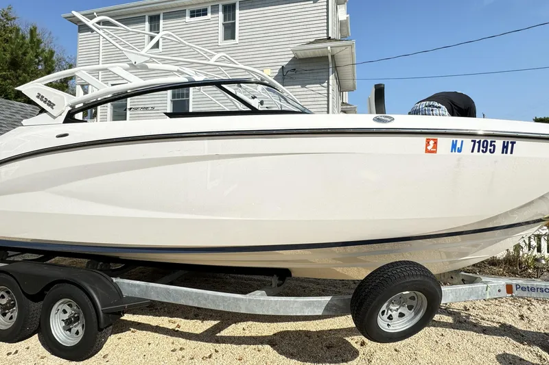 The Image of 2024 Yamaha Boats 252SE on trailer, parked near a house, with registration number visible. - 0