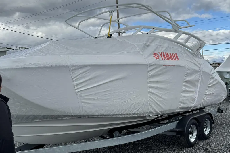 Slide: The Image of 2024 Yamaha Boats 252SE covered on trailer, cloudy sky background. - 2
