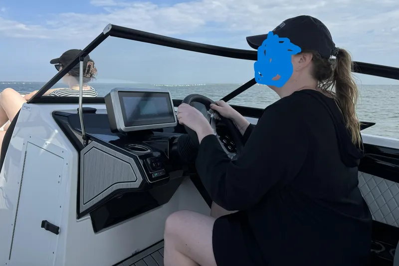 Slide: The Image of 2024 Yamaha Boats 252SE on water, person steering, another relaxing, clear sky. - 5