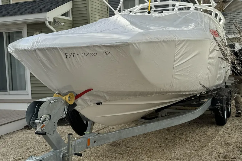 Slide: The Image of 2024 Yamaha Boats 252SE covered on trailer, parked near a house. - 6