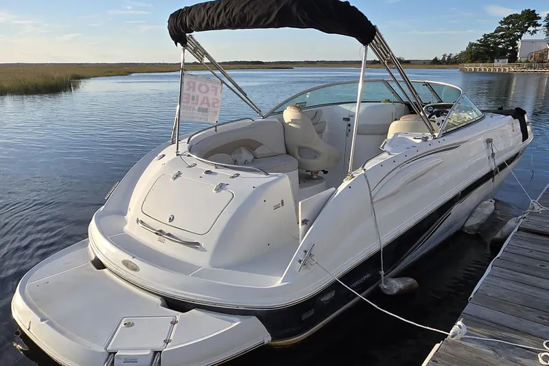 The Image of 2003 Chaparral Sunesta 233 boat docked, for sale sign visible, calm water background. - 0