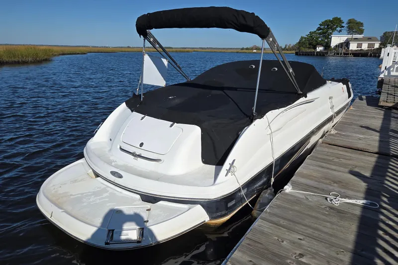 Slide: The Image of 2003 Chaparral Sunesta 233 boat docked, covered with black canvas, on a sunny day. - 1