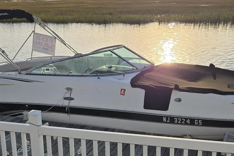 Slide: The Image of 2003 Chaparral Sunesta 233 boat docked, for sale sign visible, sunset reflection on water. - 12