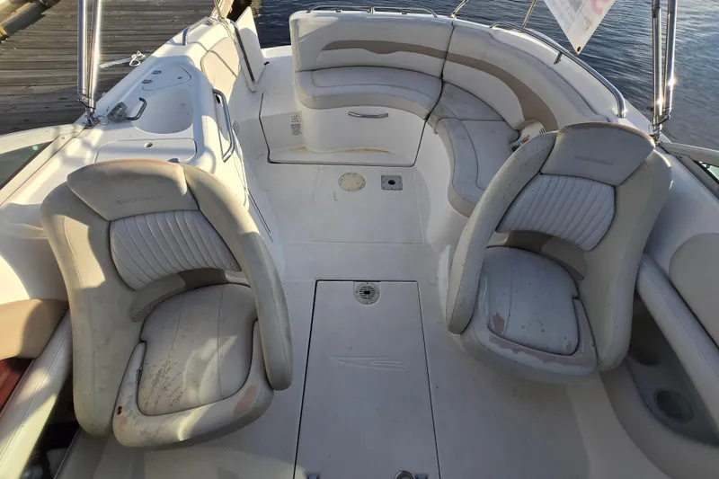 Slide: The Image of 2003 Chaparral Sunesta 233 boat interior with seating and deck, docked by the water. - 2