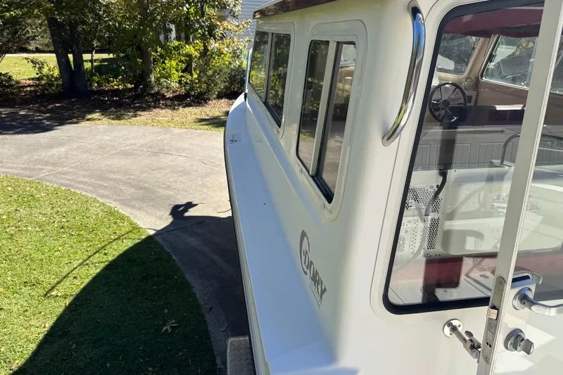 Slide: The Image of 2007 C-Dory 25 Pilothouse boat parked on a driveway, side view. - 11