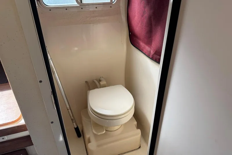 Slide: The Image of Compact marine toilet in 2007 C-Dory 25 Pilothouse boat, featuring a window and curtain. - 17