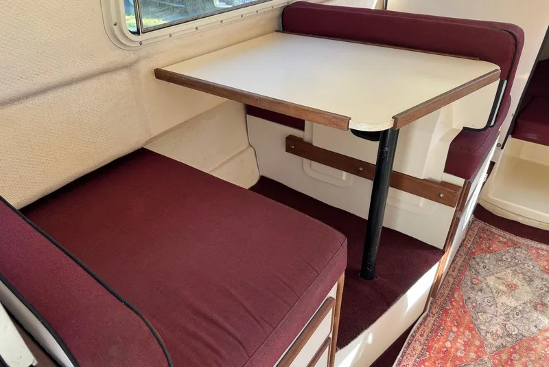 Slide: The Image of 2007 C-Dory 25 Pilothouse interior with maroon seating and foldable table. - 20