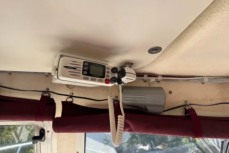 Slide: The Image of 2007 C-Dory 25 Pilothouse interior with mounted marine radio and burgundy curtains. - 25