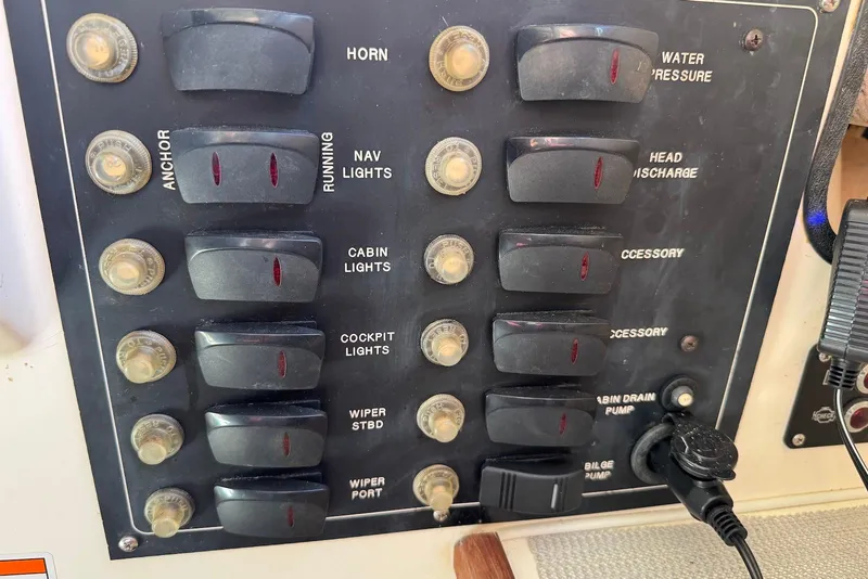 Slide: The Image of Control panel of a 2007 C-Dory 25 Pilothouse with labeled switches and buttons. - 27