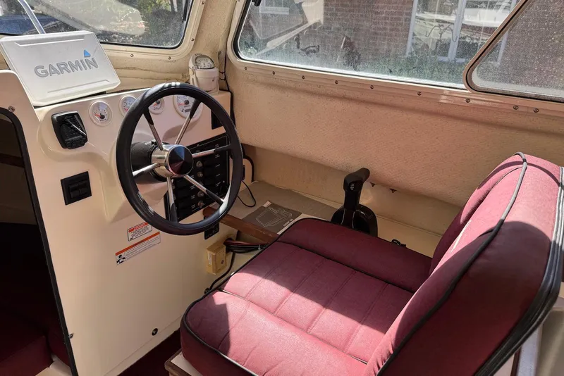 Slide: The Image of Interior of 2007 C-Dory 25 Pilothouse with steering wheel and maroon seat. - 28