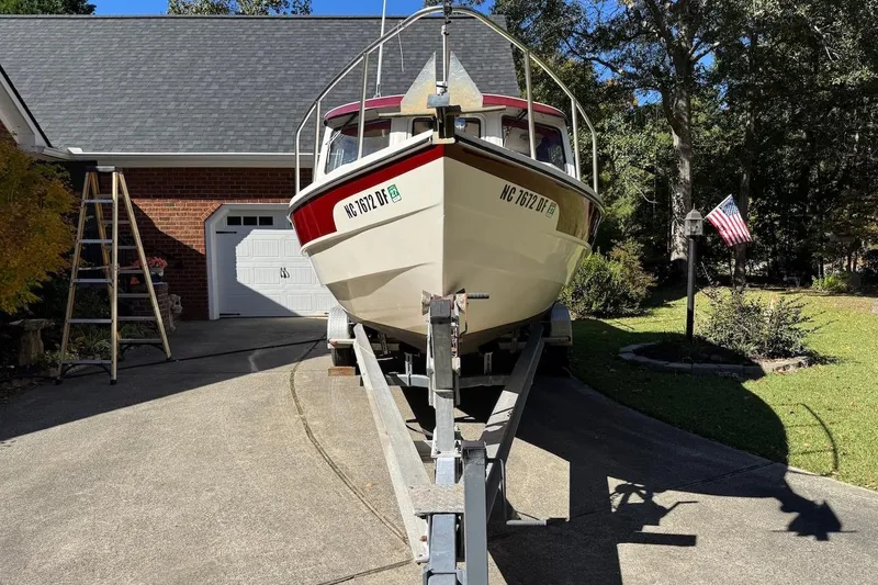 Slide: The Image of 2007 C-Dory 25 Pilothouse boat on trailer in driveway, American flag nearby. - 3