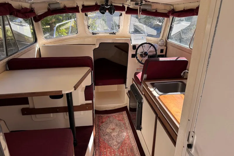 Slide: The Image of 2007 C-Dory 25 Pilothouse interior with dining area, steering wheel, and kitchenette. - 30