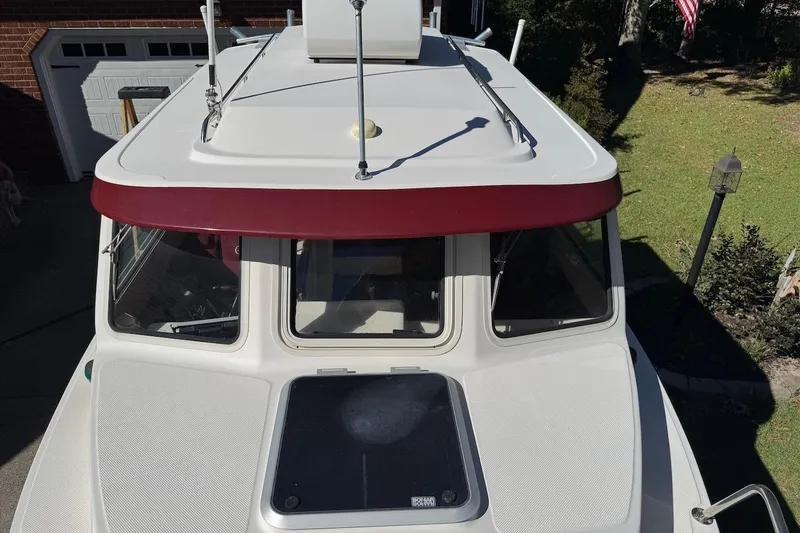 Slide: The Image of 2007 C-Dory 25 Pilothouse boat with red trim, parked in driveway. - 8