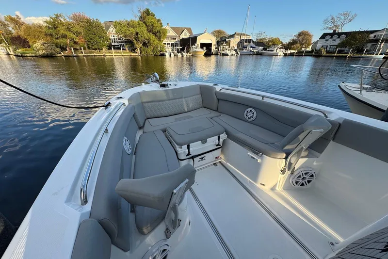 Slide: The Image of 2023 Wellcraft 262 Fisherman boat interior with gray seating, docked by a scenic waterfront. - 10