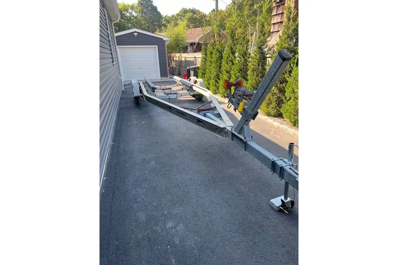 Slide: The Image of Boat trailer parked on driveway, surrounded by greenery, for 2023 Wellcraft 262 Fisherman. - 28
