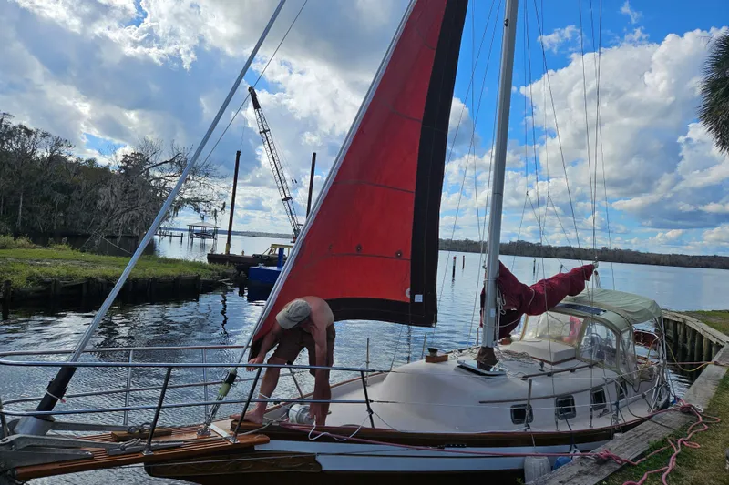 Slide: The Image of 1988 Bayfield 32C sailboat docked by a scenic waterfront under a cloudy sky. - 1
