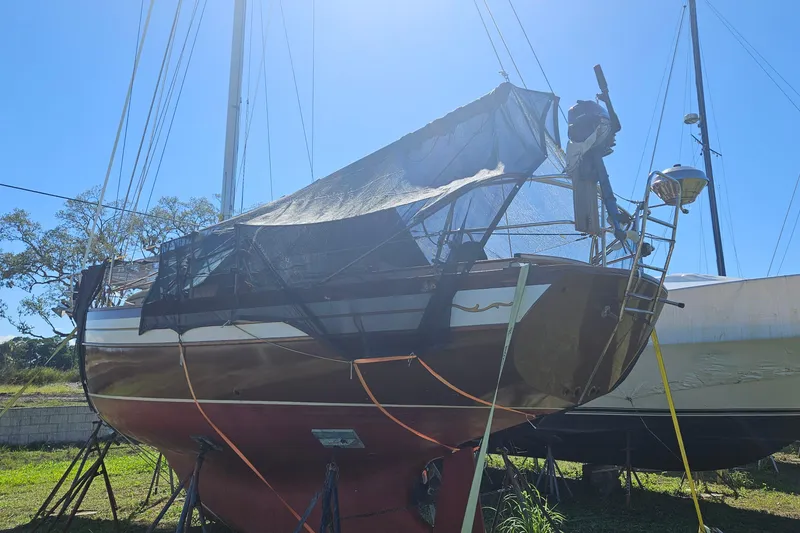 Slide: The Image of 1988 Bayfield 32C sailboat on land, covered with tarp, under clear blue sky. - 2