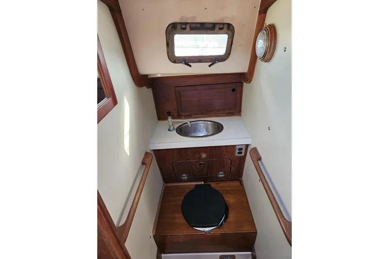 Slide: The Image of 1988 Bayfield 32C boat interior with compact bathroom, featuring a sink and toilet. - 40