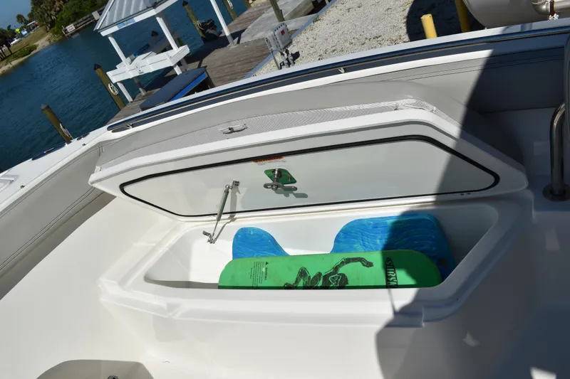 Slide: The Image of 2022 Pursuit S 268 Sport boat storage compartment with tackle boxes and cup holder. - 12