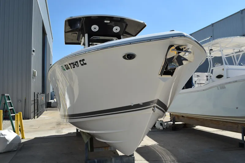 Slide: The Image of 2022 Pursuit S 268 Sport boat side view with reflection, docked near a building. - 2