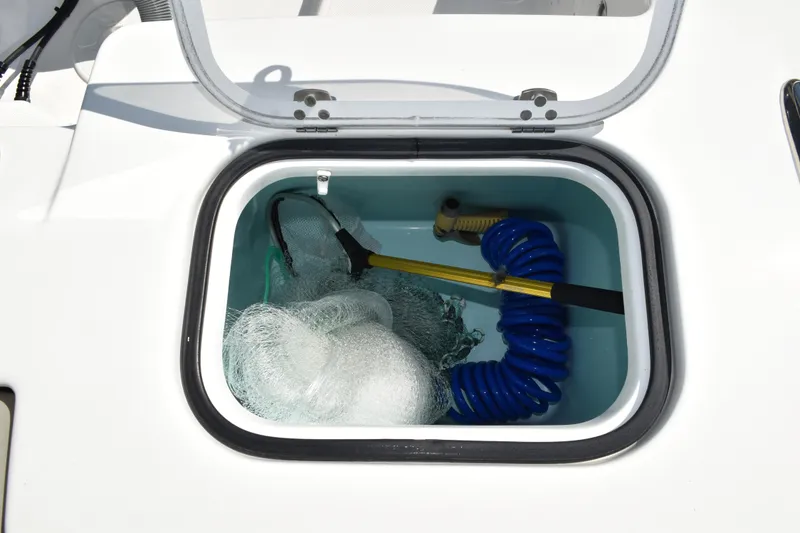 Slide: The Image of 2022 Pursuit S 268 Sport boat storage compartment with life jackets and plumbing components. - 48