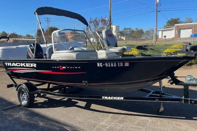 The Image of 2016 Tracker Pro Guide V-16 WT boat on trailer, black with red accents, parked outdoors. - 1