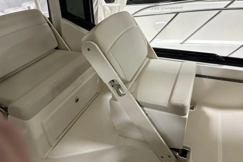 Slide: The Image of 2022 Boston Whaler 325 Conquest interior seating with white upholstery and storage compartment. - 15