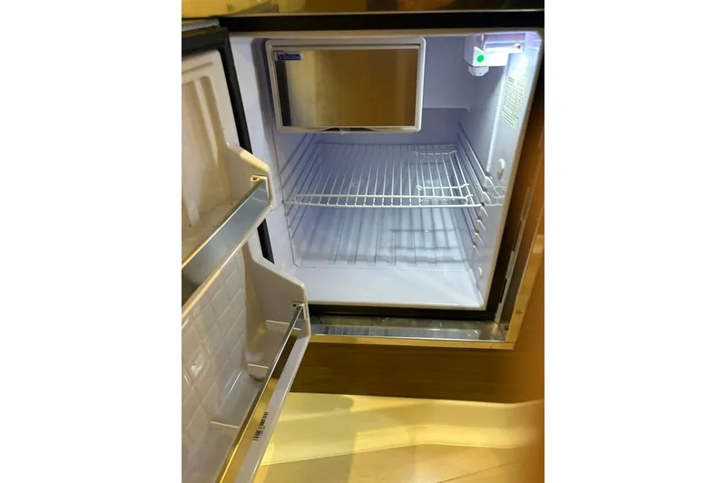 Slide: The Image of Open mini fridge inside 2022 Boston Whaler 325 Conquest boat, showing empty shelves. - 27