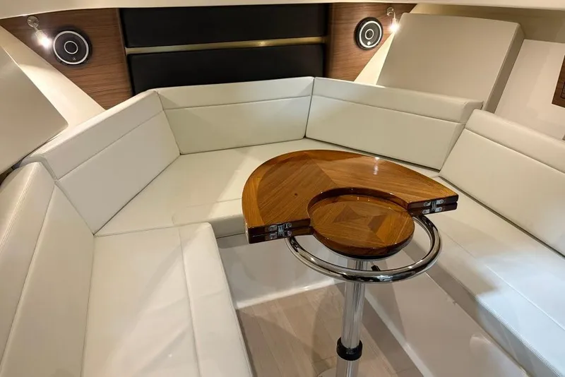 Slide: The Image of 2022 Boston Whaler 325 Conquest interior with white seating and wooden table. - 29