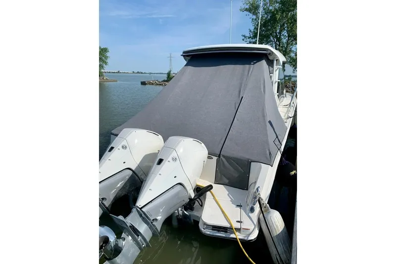 Slide: The Image of 2022 Boston Whaler 325 Conquest boat docked with covered deck and dual outboard engines. - 3