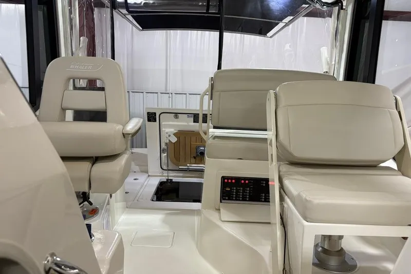 Slide: The Image of 2022 Boston Whaler 325 Conquest interior with beige seating and control panel. - 38