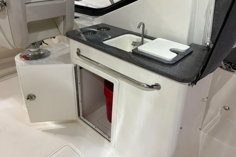 Slide: The Image of 2022 Boston Whaler 325 Conquest boat galley with sink, cutting board, and storage. - 41