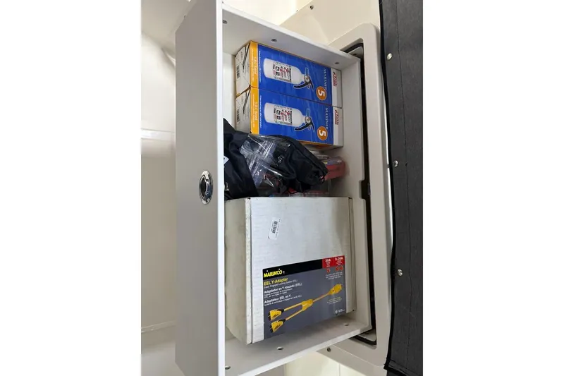 Slide: The Image of Storage compartment on a 2022 Boston Whaler 325 Conquest, containing various tools and supplies. - 42