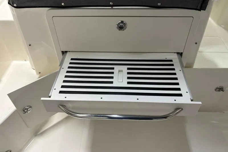 Slide: The Image of 2022 Boston Whaler 325 Conquest boat storage compartment with pull-out tray and handle. - 43