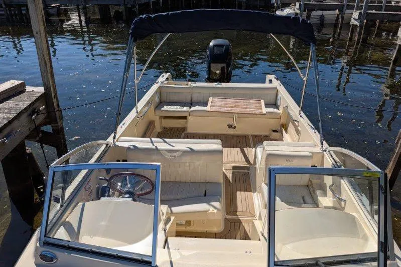 Slide: The Image of 2017 Rossiter R23 boat with open deck, seating, and canopy on calm water. - 3